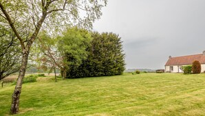 A grassy field with a house and trees. - Jura Cottage | Peat Inn (Peat Inn)