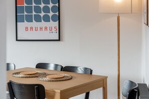 A dining area with a wooden table, black chairs, and a framed artwork on the wall.