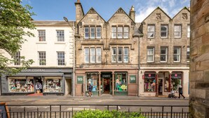 A street view with a row of shops, including a store named 'Cook Central' and another with 'White Stuff' signage. - Spire View Apartment (St Andrews)