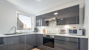 A modern kitchen with stainless steel appliances, a built-in oven, and a microwave. - Spire View Apartment (St Andrews)