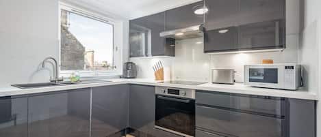 Una cocina moderna con armarios oscuros, horno integrado y microondas.