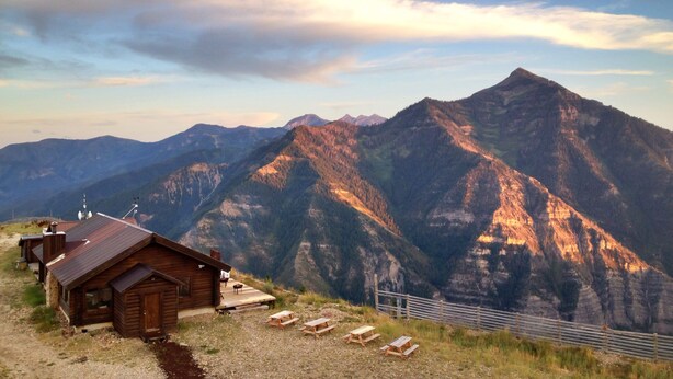 A wooden cabin with a metal roof, a wooden deck, and picnic tables. - 4-bedroom cabin Chalet Nestled in the Sundance Mountains (Provo)
