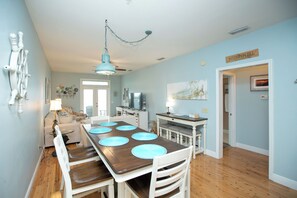 A dining area with a wooden table, white chairs, and blue placemats.