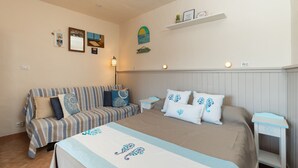 Een slaapkamer met een bed, een gestreepte bank, een nachtkastje en een plank met decoratieve objecten.
