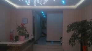 A hallway with a reception desk, a staircase, and potted plants. - Jingyi Hotel (Huize)