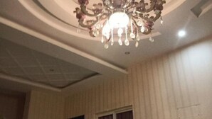 A room with a decorative chandelier, a window with curtains, and a door. - Jingyi Hotel (Huize)
