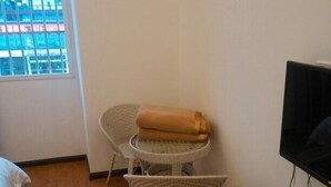 A small room with a bed, a TV, a coffee maker, and two wicker chairs. - Jingyi Hotel (Huize)