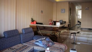 A hotel room with a sofa, a small table, and a chair. There is a desk with a computer and a lamp. The room has striped wallpaper and a chandelier. - Jingyi Hotel (Huize)