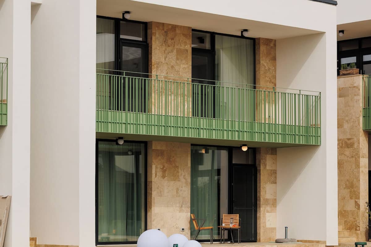 Una casa moderna de dos pisos con balcón, piscina y césped bien cuidado.