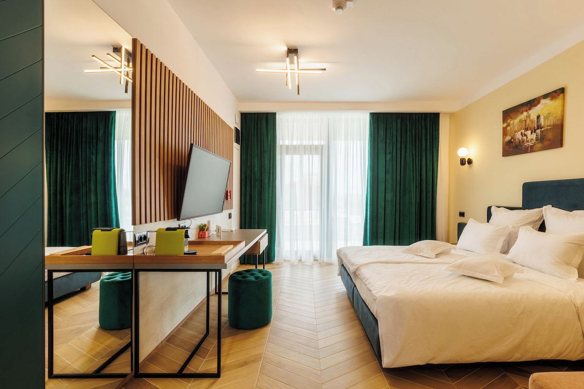 Una habitación de hotel con cama, un escritorio con computadora, televisión y un cuadro en la pared.