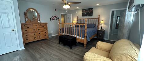 Ein Schlafzimmer mit einem hölzernen Bett, einem Schminktisch, einem Stuhl, einem Deckenventilator und einem Fahrrad an der Wand.