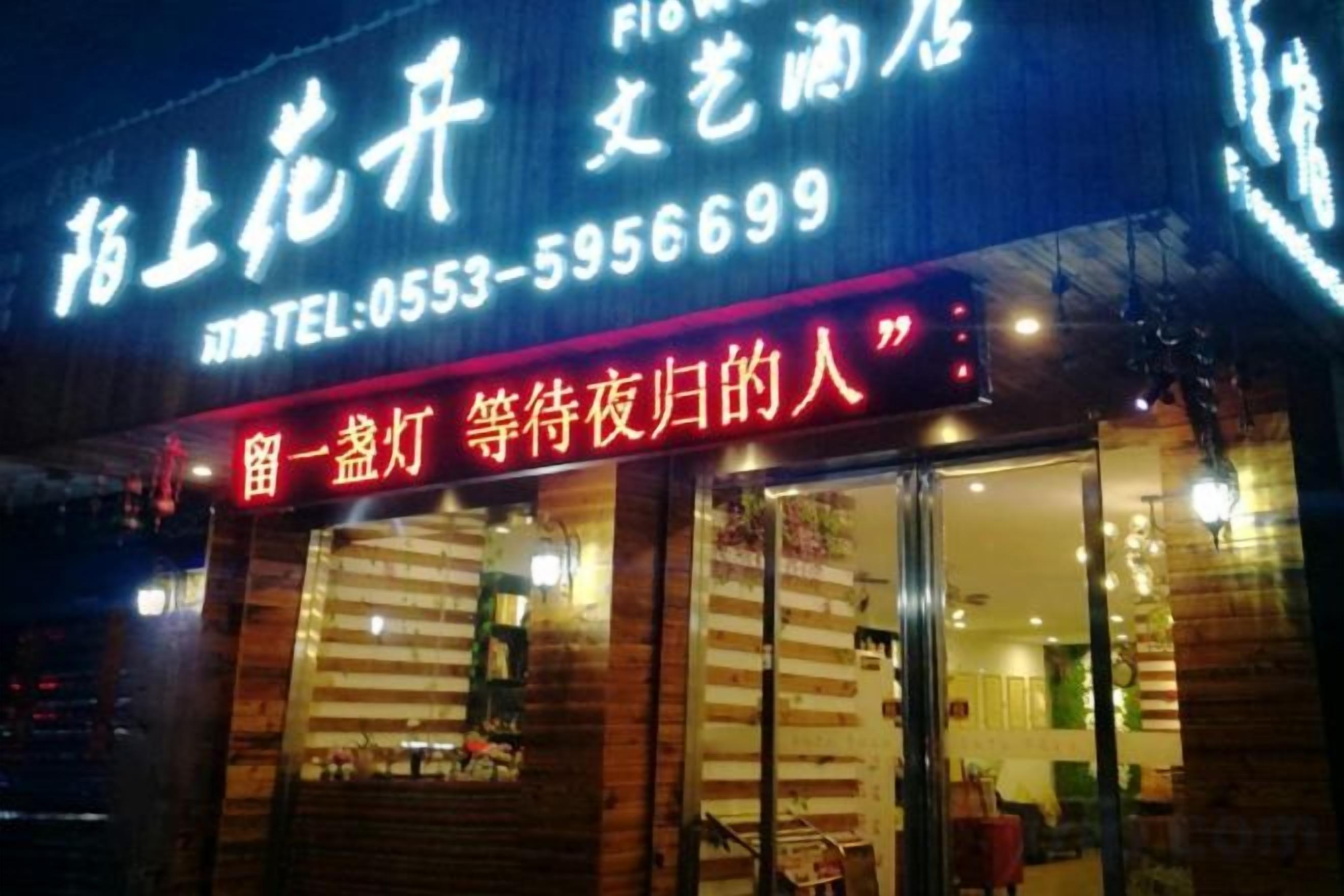 A hotel with a visible entrance and signage, including a contact number.