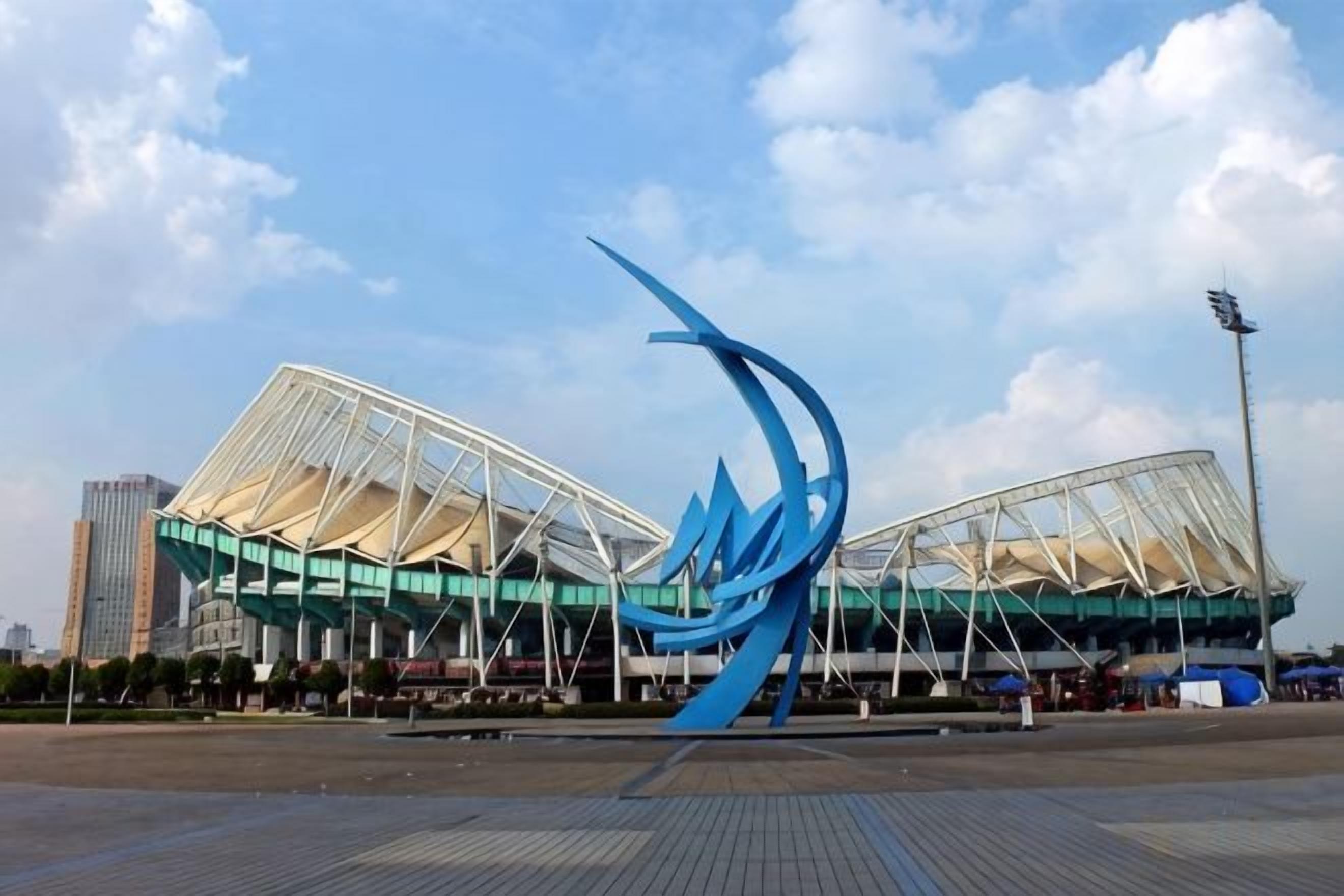 A stadium with a distinctive blue sculpture in the foreground.