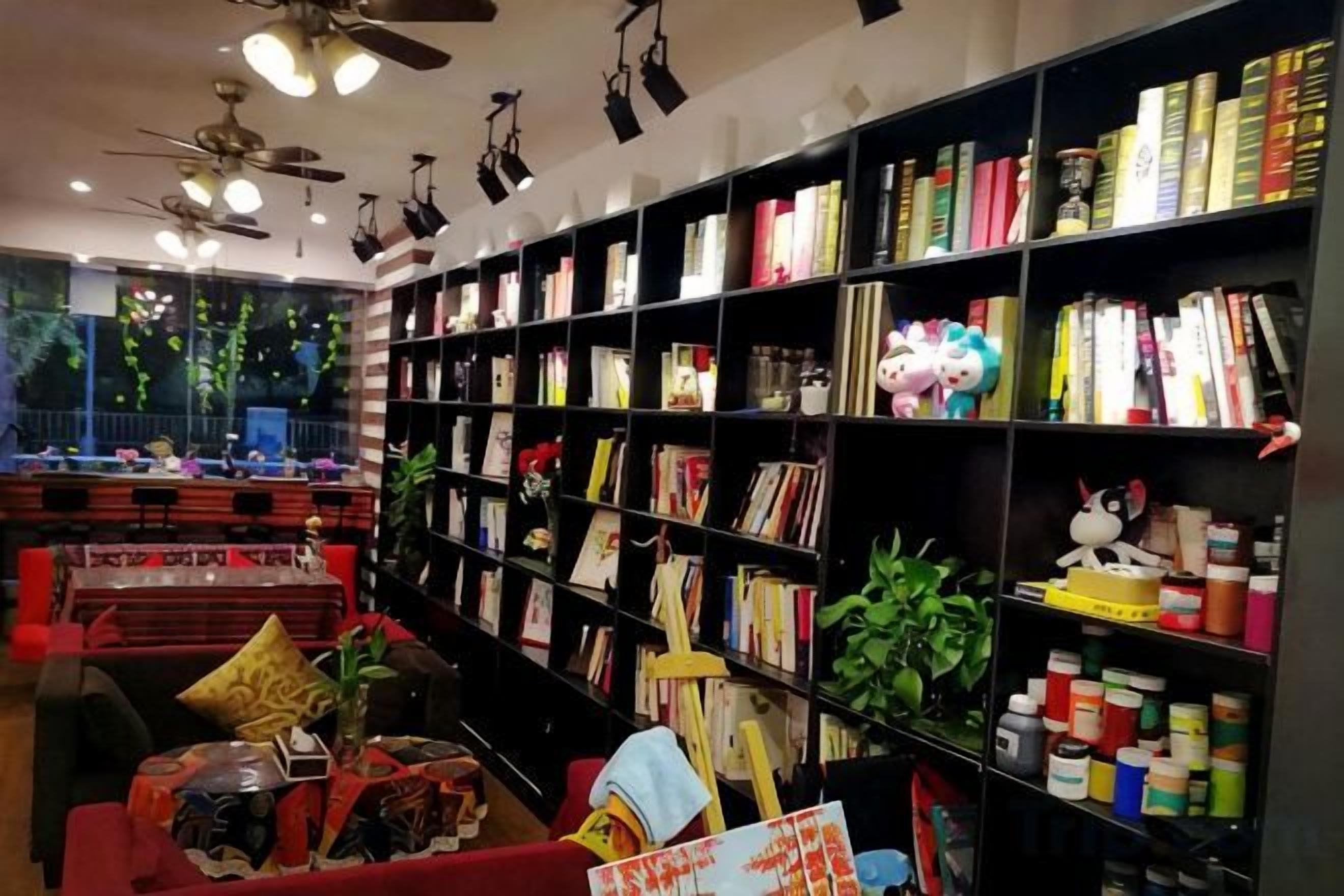 A library with bookshelves, ceiling fans, and a red sofa.