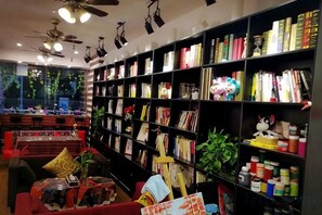 A library with bookshelves, ceiling fans, and a red sofa.