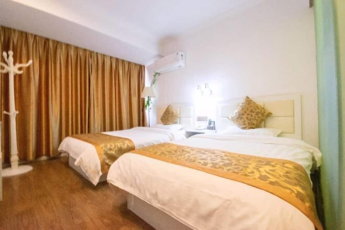 Habitación de hotel con dos camas, un perchero, un aire acondicionado y una ventana con cortinas.