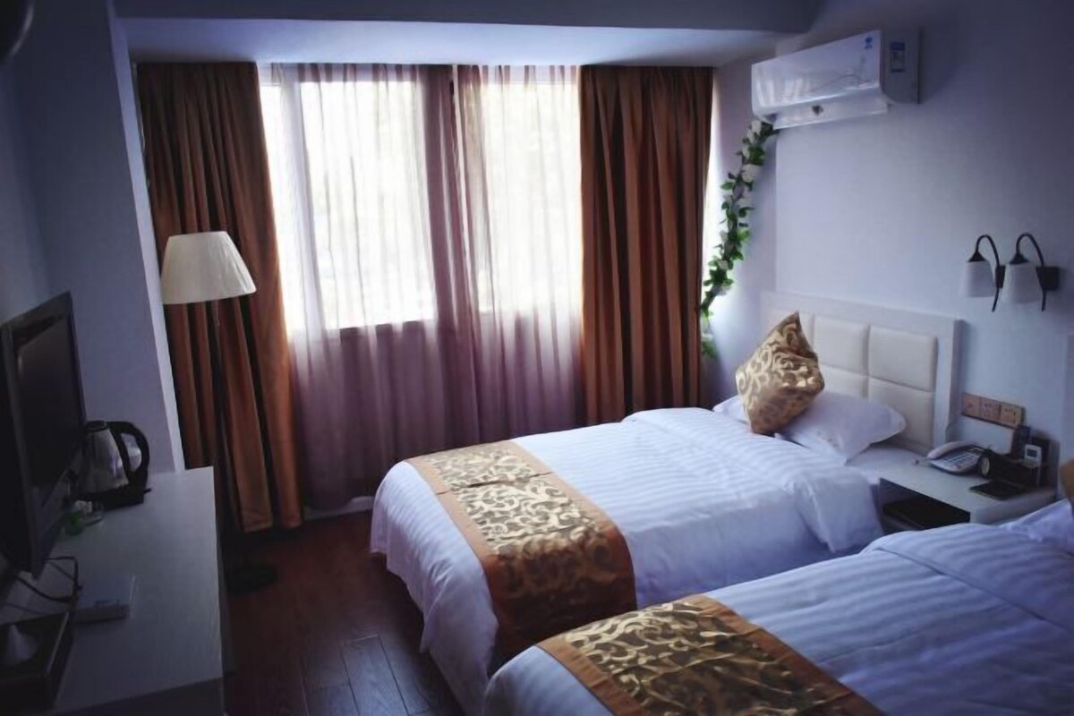 Habitación de hotel con dos camas, un escritorio con lámpara y televisión.