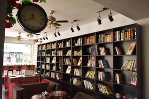 Une bibliothèque avec des étagères, une horloge et des ventilateurs de plafond.