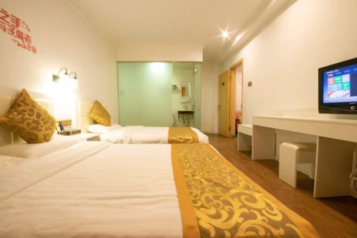 Habitación de hotel con dos camas, un escritorio, televisor y espejo.
