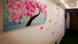Un pasillo con un cuadro grande de flores rosas en la pared, una puerta y una alfombra verde.