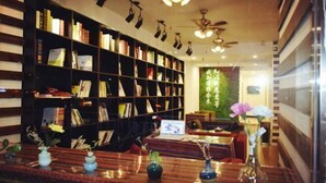 Una biblioteca con estanterías, un ordenador portátil sobre una mesa y jarrones con flores.