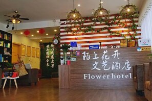 Ein Empfangsschalter mit einem Schild, auf dem 'Flowerhotel' steht, und einer Holztresen.