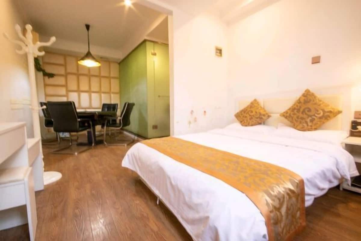 Habitación de hotel con cama, escritorio y silla. Una pared es verde y otra es blanca.