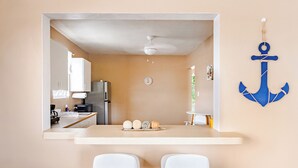 A compact kitchen with white cabinets, a countertop, and a ceiling fan. There are two white bar stools in front of the counter. - 5 minutes from Seven Seas Beach Quiet Escape in Fajardo with Ocean View (Fajardo)