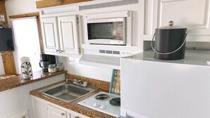 Une cuisine avec des armoires blanches, un comptoir en granit, un évier en acier inoxydable, un four à micro-ondes, une cuisinière et un réfrigérateur.