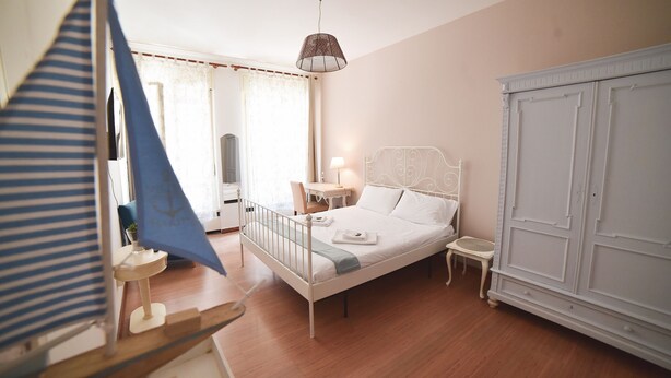 Une chambre à coucher comprenant un lit, des tables de chevet, une armoire et un luminaire suspendu.