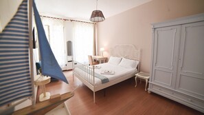 Une chambre à coucher comprenant un lit, des tables de chevet, une armoire et un luminaire suspendu.