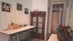Une cuisine avec un long comptoir, des tabourets, un meuble en bois et un luminaire suspendu.