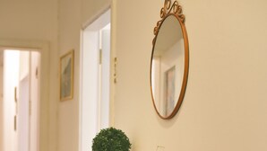 Une commode en bois avec des tiroirs, un panier en osier, une bouteille verte et un miroir accroché au mur.