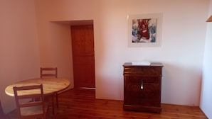 Um quarto com uma mesa de jantar de madeira, cadeiras, um armário de madeira e um quadro na parede.