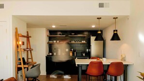 A modern kitchen with a dining area, wooden shelves, and red chairs. - Sosuite | 2BR Apt w Laundry, Private Entrance (Philadelphia)