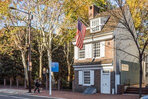Ein historisches Gebäude mit einer gut sichtbaren amerikanischen Flagge, einer Ziegel-Fassade und einer weißen Tür.