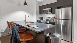 A modern kitchen with a central island, stainless steel appliances, and pendant lighting.
