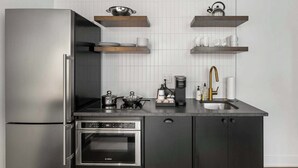 A modern kitchen with a stainless steel refrigerator, built-in oven, and a coffee maker. - Sosuite | Studio Apt w Laundry, Courtyard View (Philadelphia)