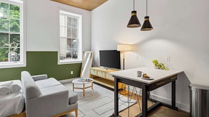 En moderne stue med sofa, lille bord, fjernsyn og lampe.