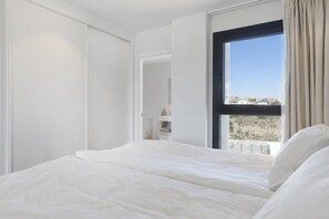 A bedroom with a large bed, a wardrobe, and a window with a view. - Luxury Apartment with Terrace in Higueron (Fuengirola)