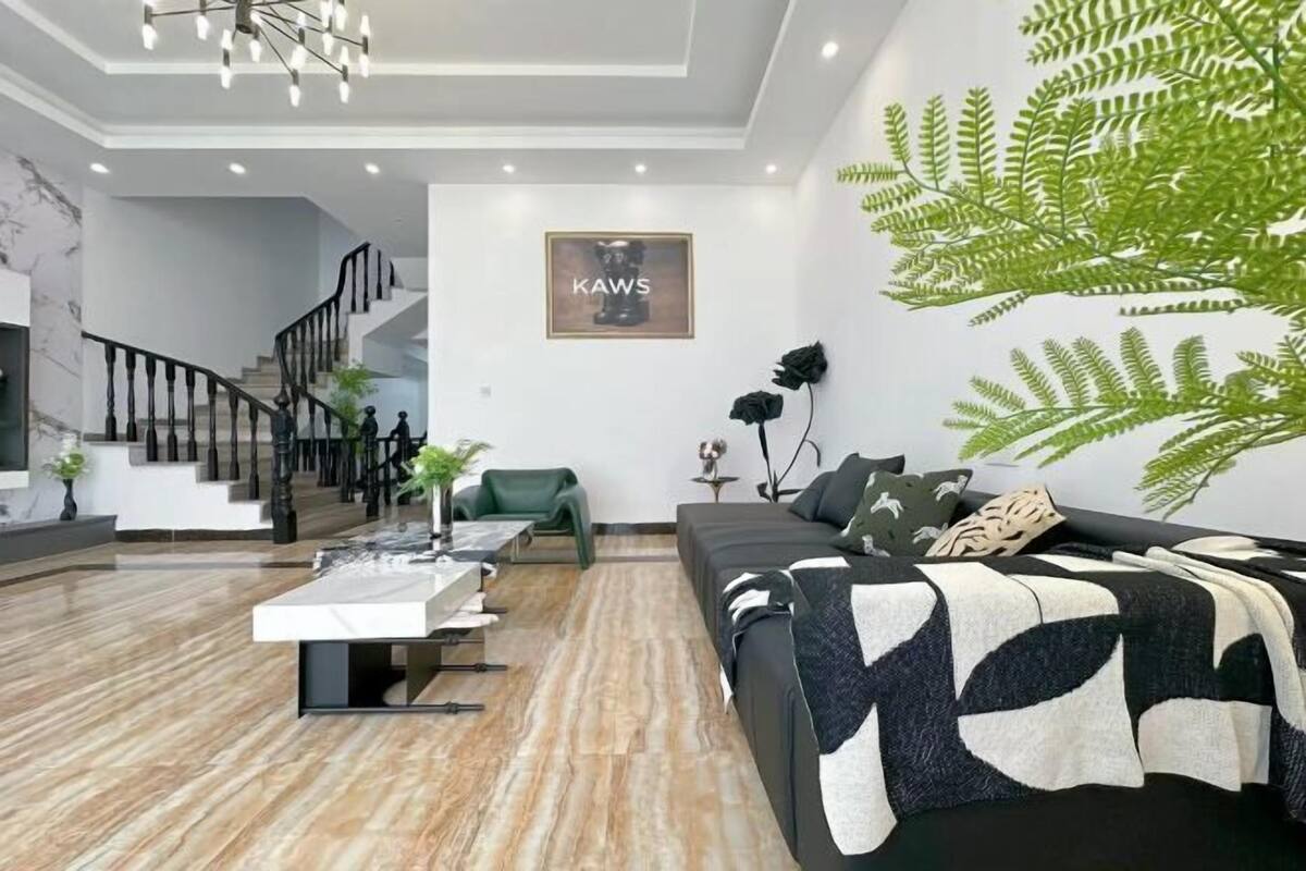 Un salon moderne avec un escalier, un canapé, une table basse et une fougère fixée au mur.