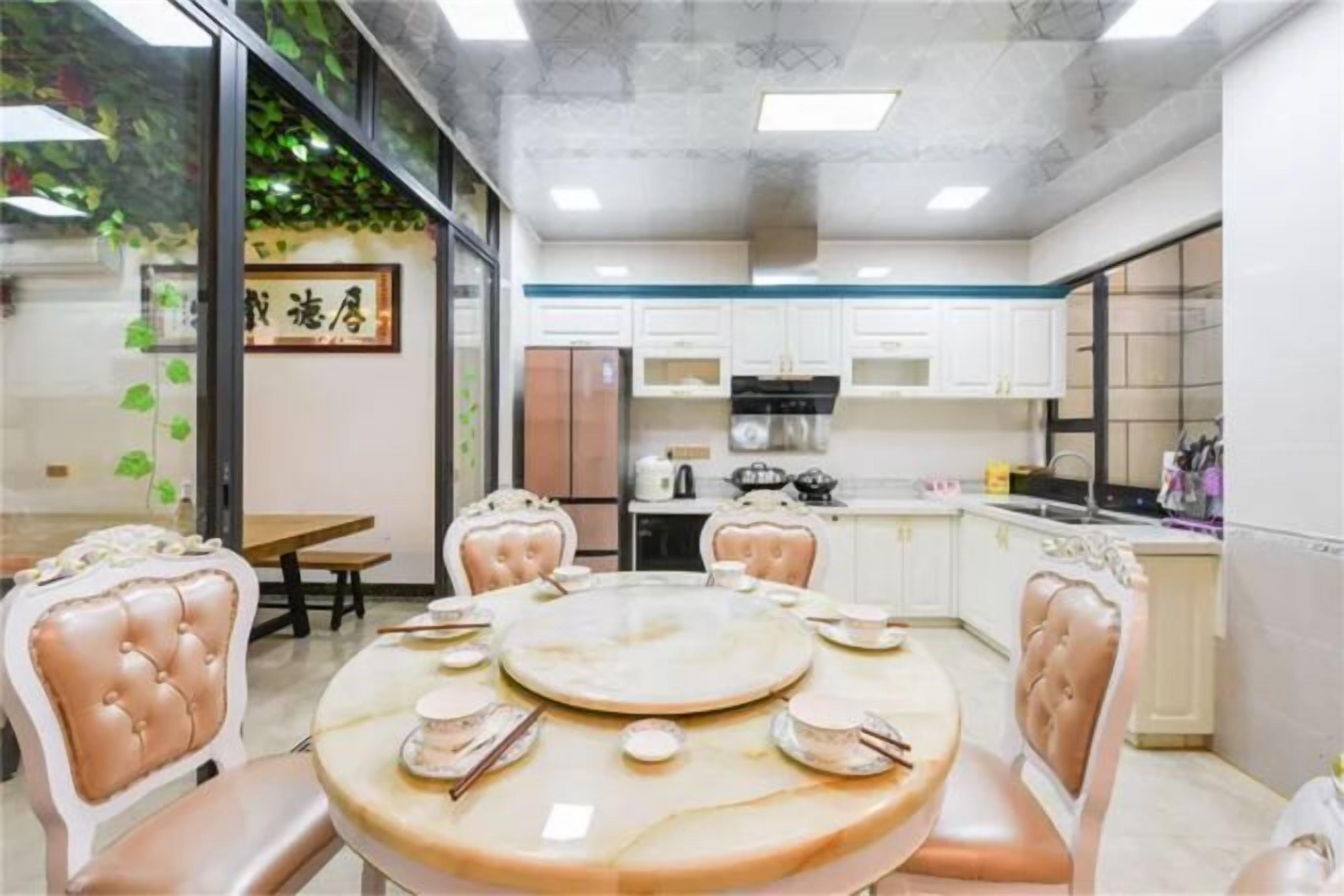 A dining area with a round table, chairs, and a kitchen in the background.