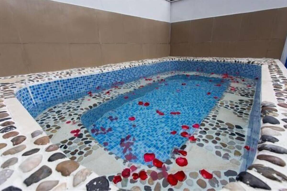 Un bain à remous rectangulaire doté d’un revêtement de sol en mosaïque et bordé de galets.