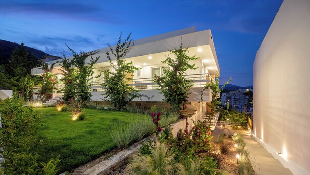 Una casa moderna con un jardín cuidado, un camino y un balcón.