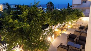 Un área de estar al aire libre con muebles de mimbre y vista al mar al atardecer.