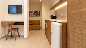 Una cocina moderna con refrigerador empotrado, una mesa de comedor de madera con una silla, un sofá y un televisor de pantalla plana montado en la pared.