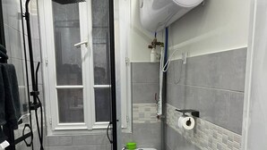 Ein kleines Badezimmer mit Duschkabine, Toilette und Waschbecken.