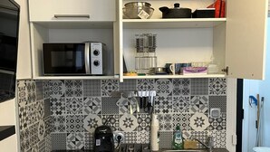 Eine Küche mit weißen Schränken, einer Mikrowelle, einer Kaffeemaschine und einem Spülbecken.