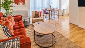 Una sala de estar moderna con un sofá rojo, una mesa redonda de madera y un comedor con una silla roja y una mesa blanca.