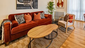 Una sala de estar moderna con un sofá rojo, una mesa de centro de madera y un comedor con mesa y sillas de madera.